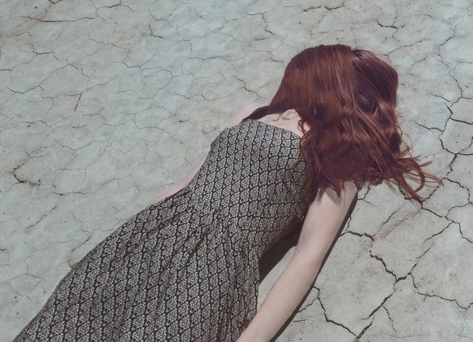 #im freien Fall. Eine junge frau in einem Abendkleid liegt wie tot auf dem Gesicht liegend auf einem Straßenpflaster.